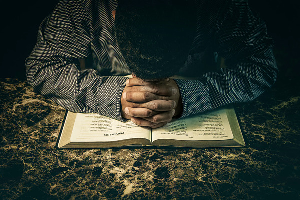 Christian man praying with Bible open