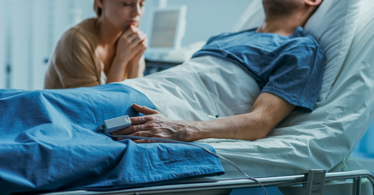 person praying in hospital bed