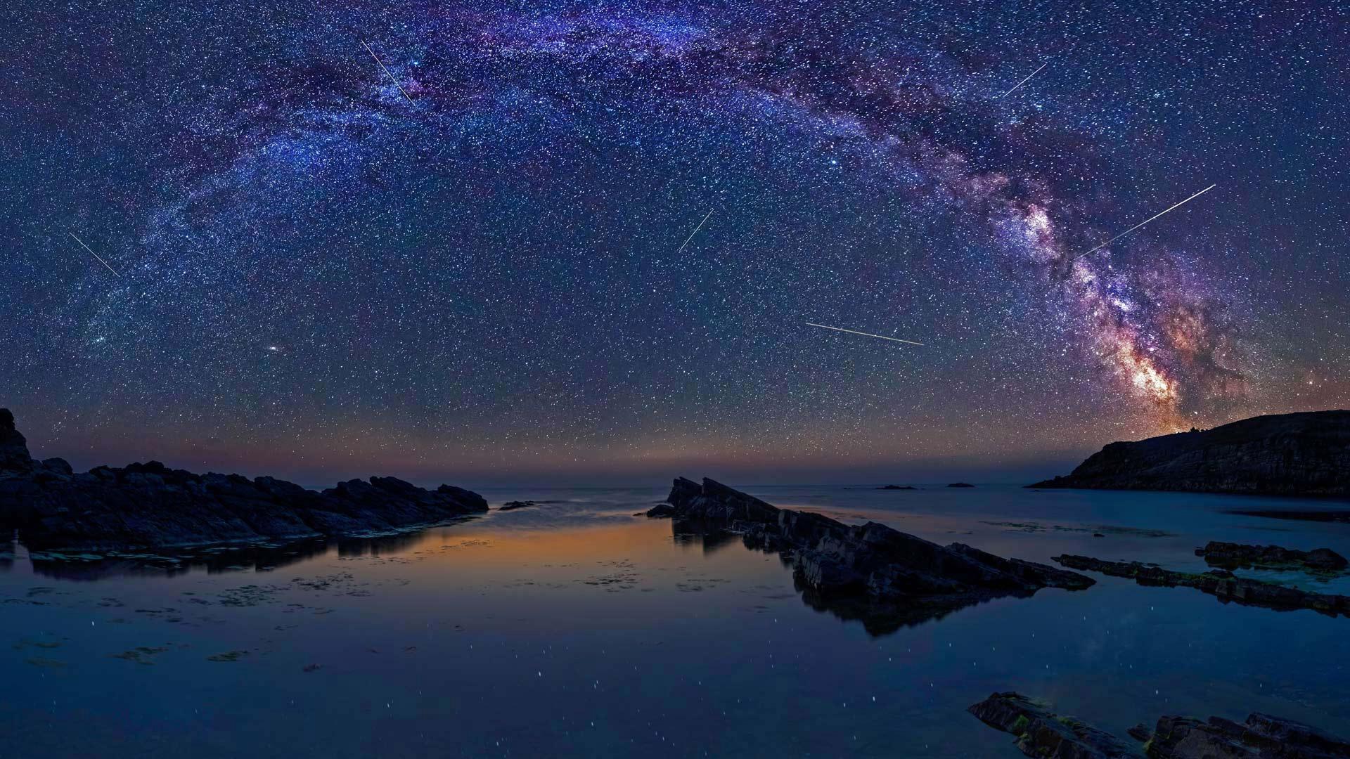 Star-covered night sky over ocean horizon